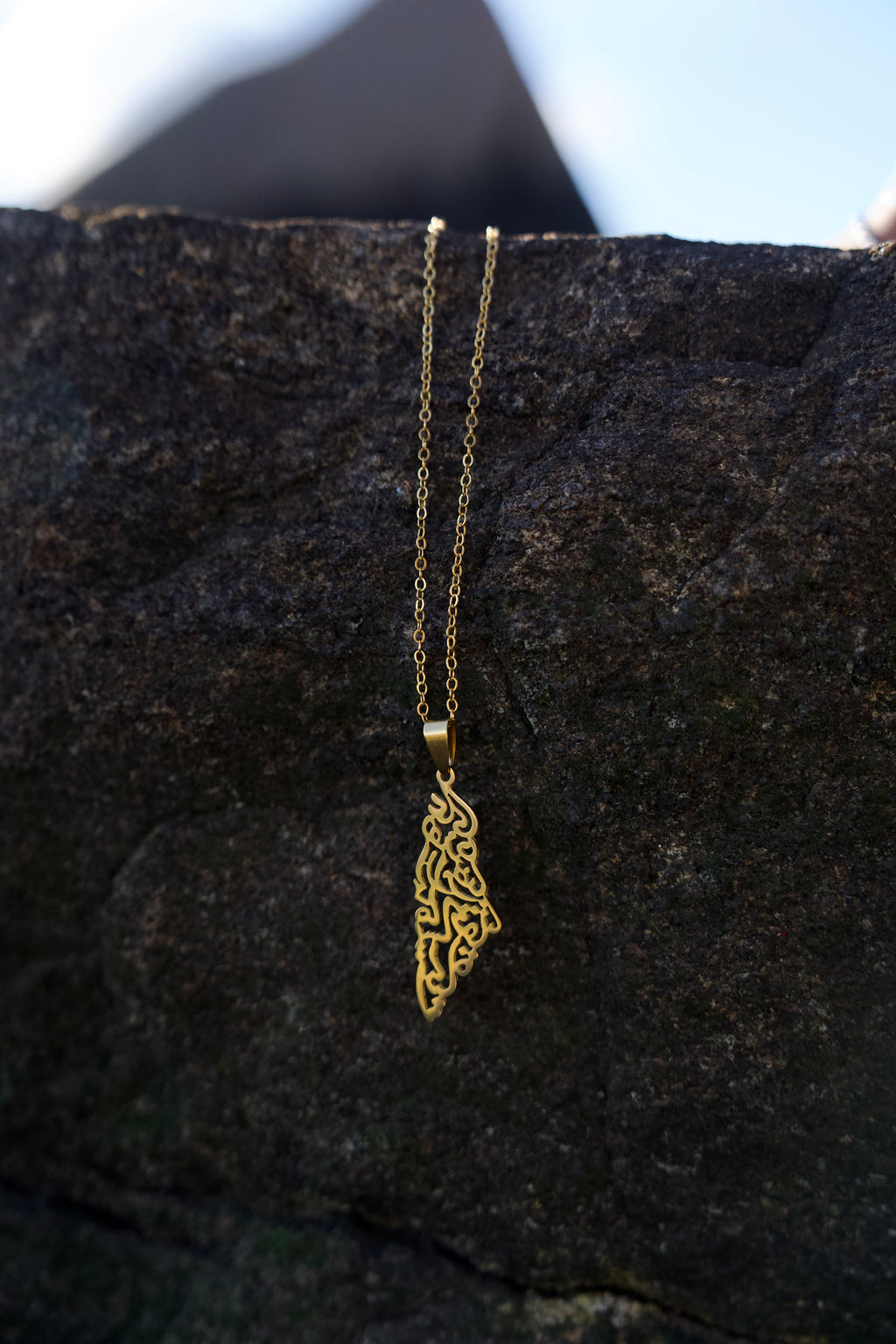 Gold necklace with a decorative pendant on a dark textured surface