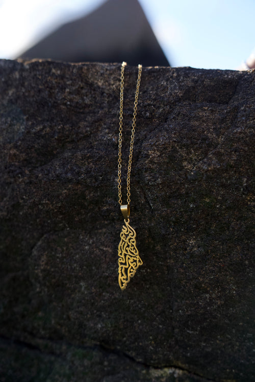 Gold necklace with a decorative pendant on a dark textured surface
